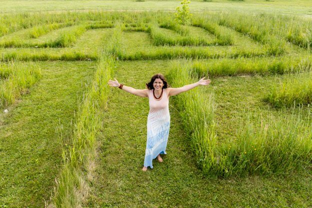Brenda with her arms open wide in the labyrinth at A&B Healing Resort